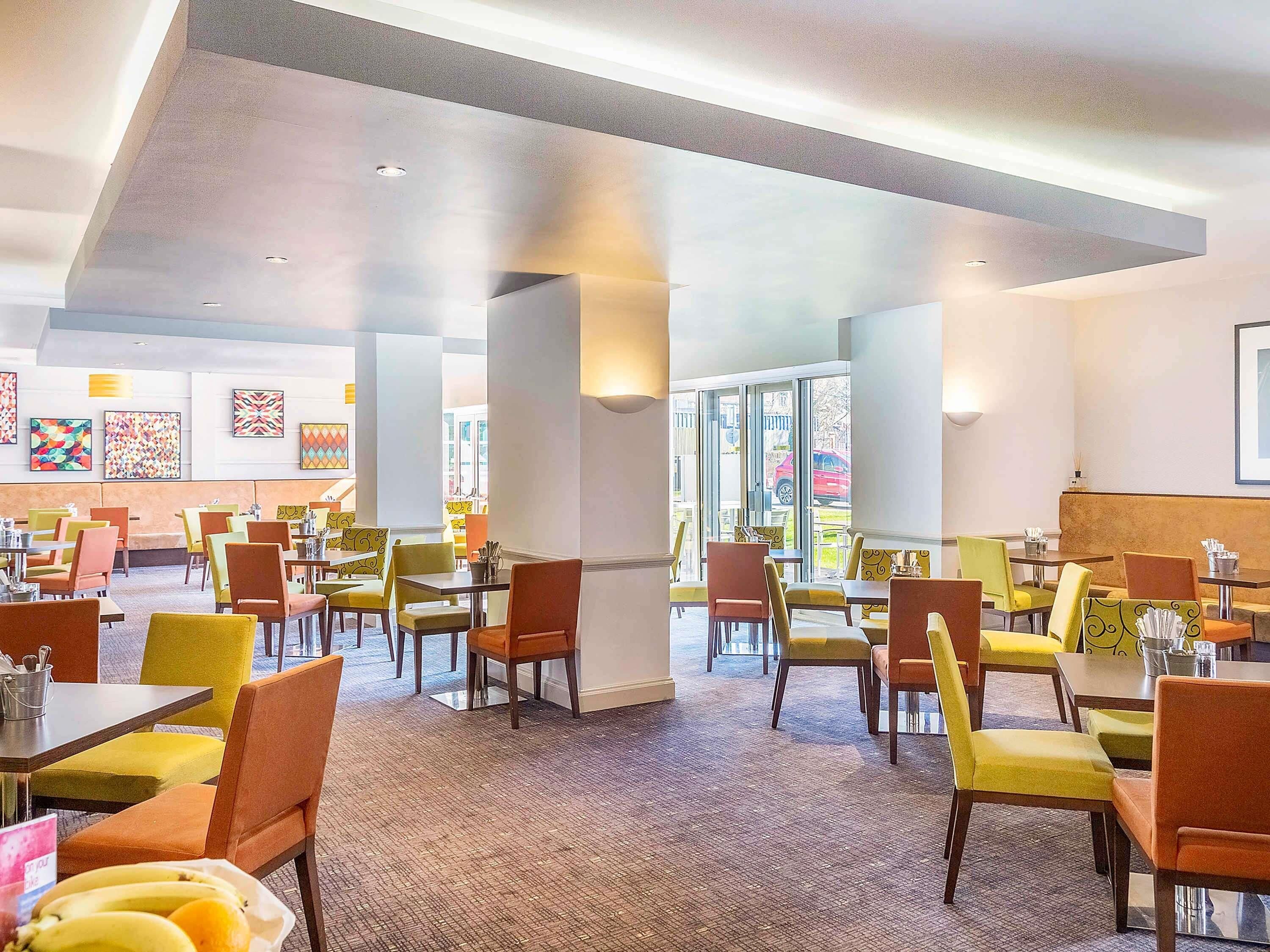 A spacious restaurant with high ceilings, multiple seating areas, and large windows allowing natural light.
