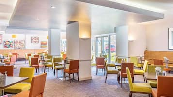 A spacious restaurant with high ceilings, multiple seating areas, and large windows allowing natural light.