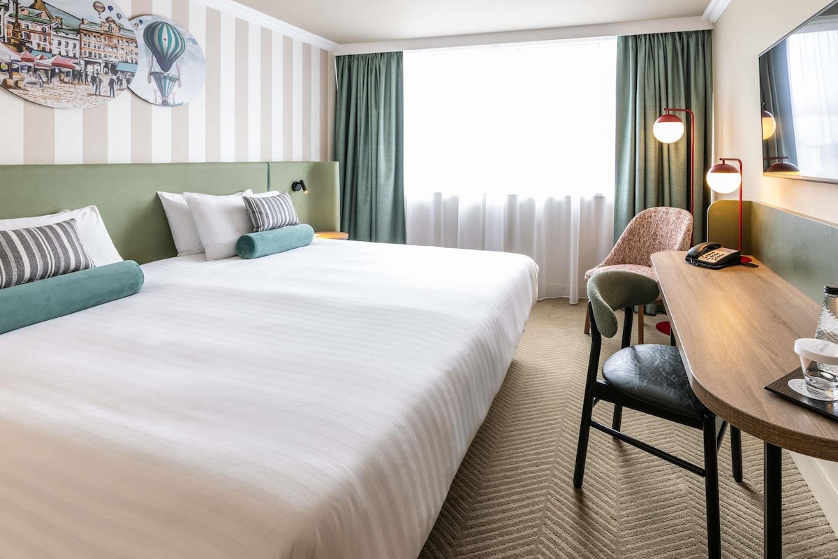 Una habitación de hotel con una cama grande, un escritorio con teléfono y una silla.