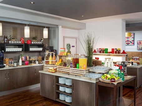 A modern kitchen with a central island, various food items, and a coffee station.