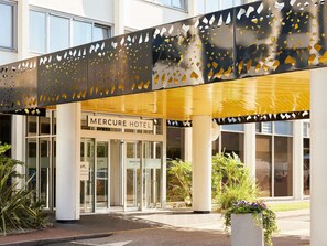 A hotel entrance with a modern design, featuring a glass door entrance, a signboard, and a decorative metal canopy. - Mercure Northampton (Northampton)