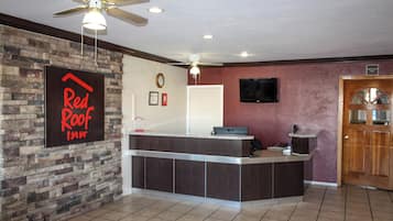 Una mesa de recepción con un reloj y un cartel de Red Roof Inn.