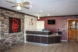 Balcão de recepção com relógio e placa da Red Roof Inn.