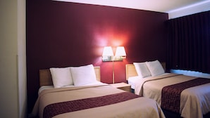 A hotel room with two beds, a red wall, and a nightstand with a lamp. - Red Roof Inn Blythe (Blythe)