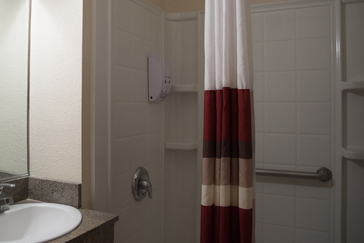 A bathroom with a white sink, a mirror, a shower curtain, and a towel rack.