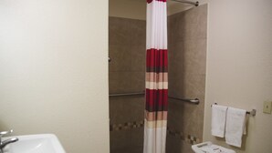 A bathroom with a shower, a sink, and a towel rack. - Red Roof Inn Blythe (Blythe)
