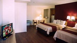A hotel room with two beds, a TV, a desk with a chair, and a lamp. - Red Roof Inn Blythe (Blythe)