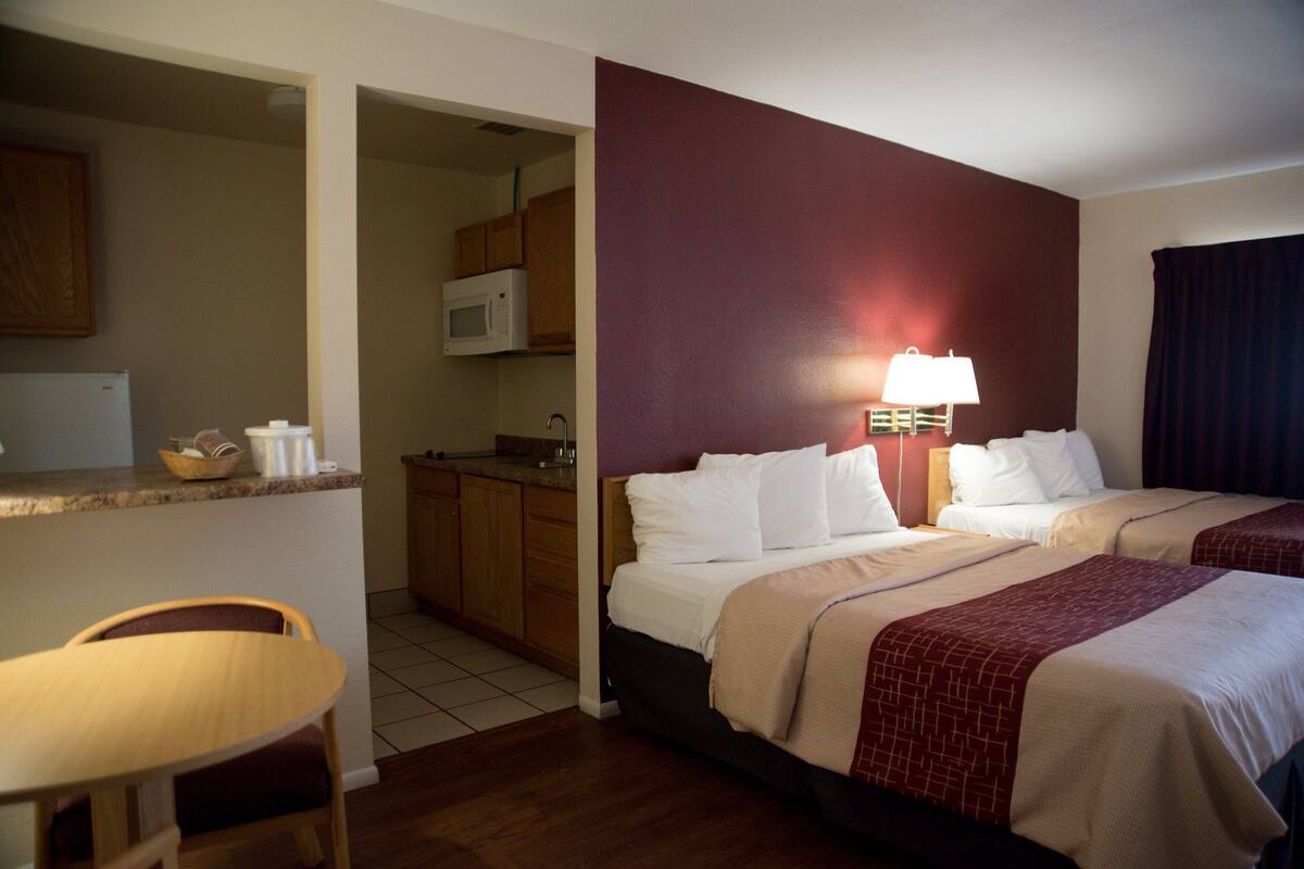 Ein Hotelzimmer mit zwei Betten, einer Küchenzeile, einem Essbereich und einem Badezimmer.