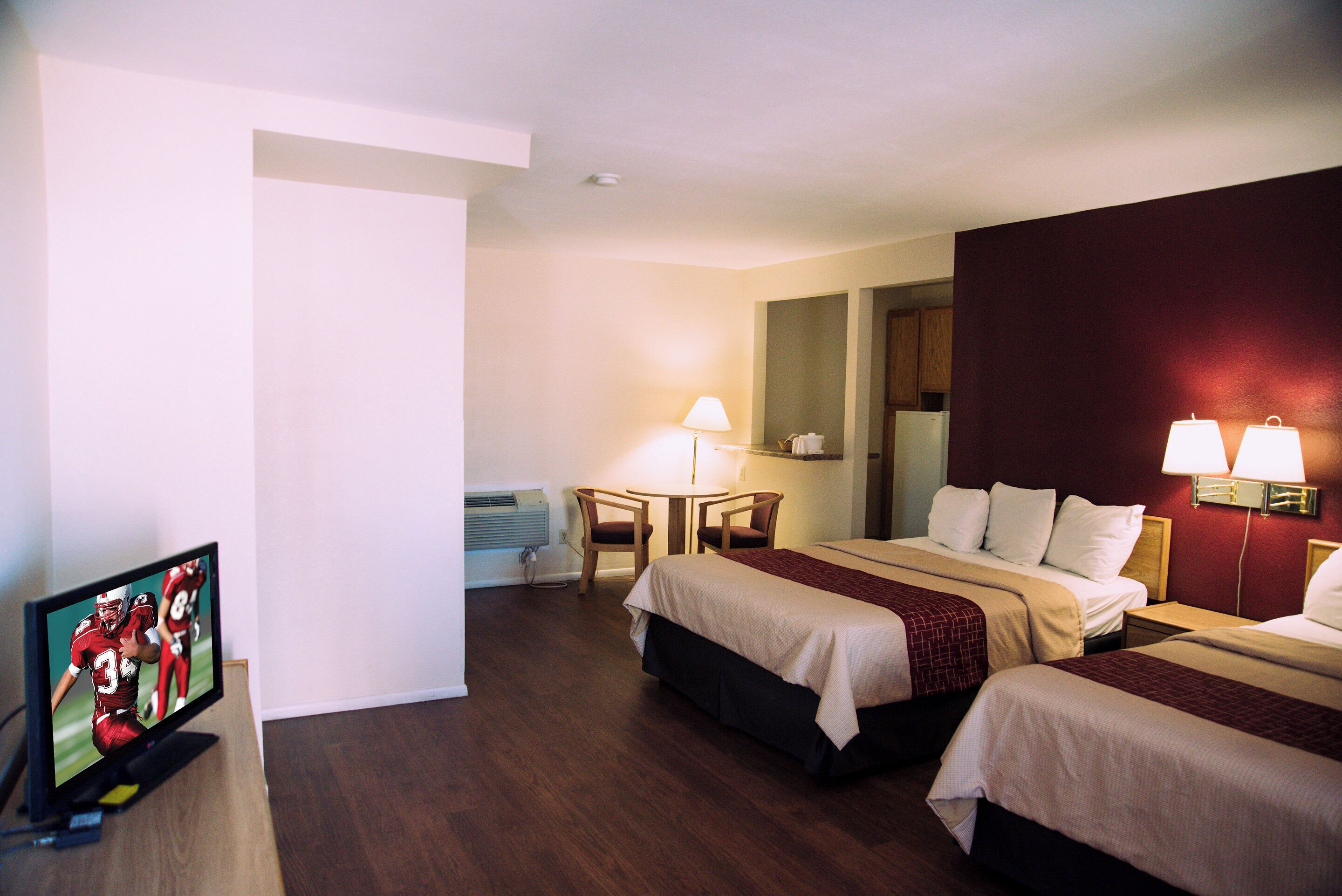 Ein Hotelzimmer mit zwei Betten, einem Schreibtisch, einem Stuhl und einem Fernseher.
