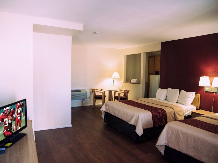 Una habitación de hotel con dos camas, un escritorio, una silla y un televisor.