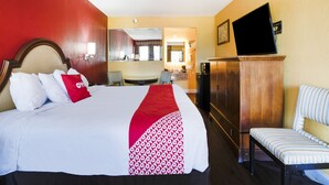 Una habitación de hotel con una cama grande, un escritorio, una silla, un televisor y un armario.