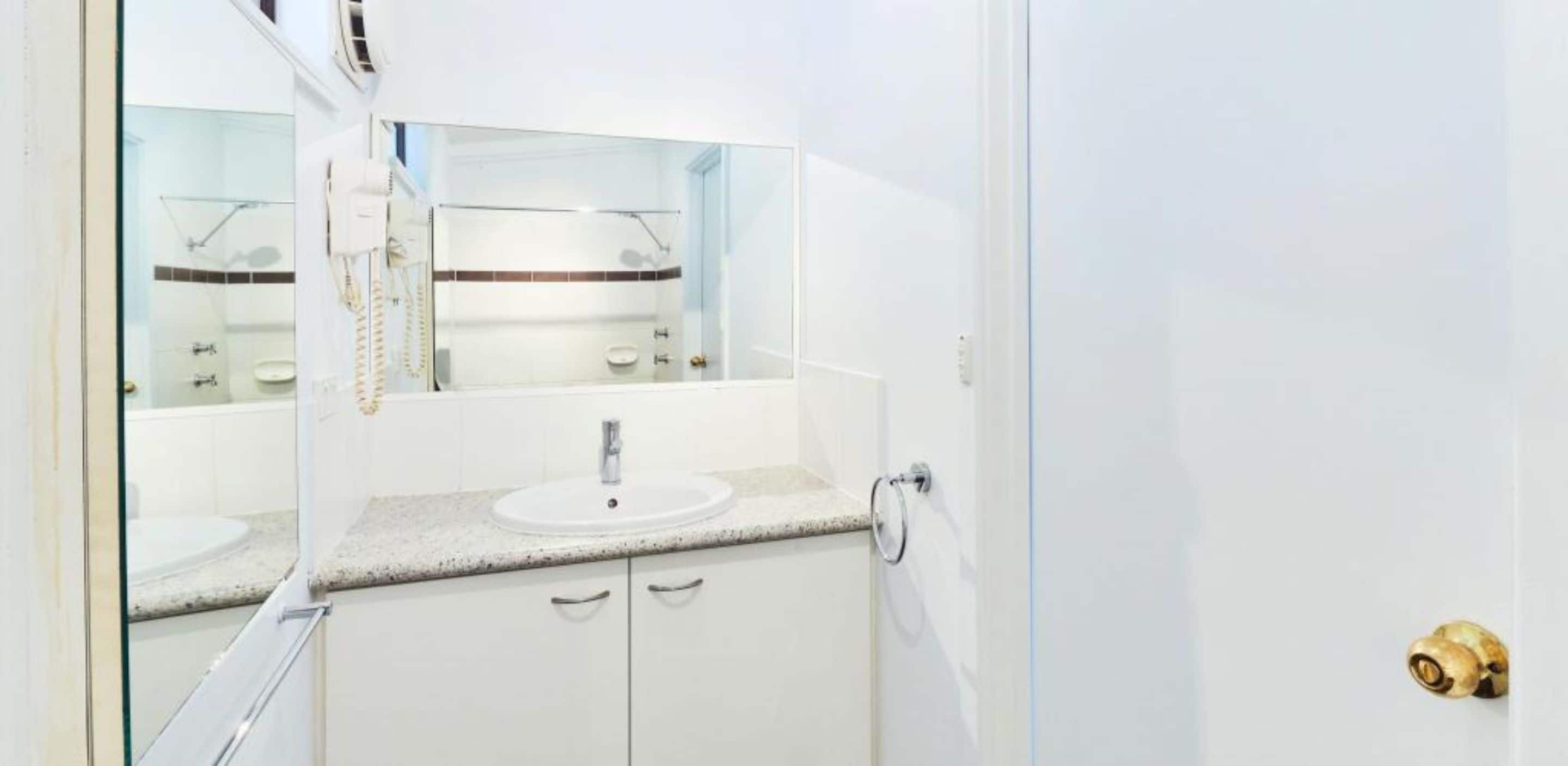 A bathroom with a white sink, a mirror, and a glass shower enclosure.