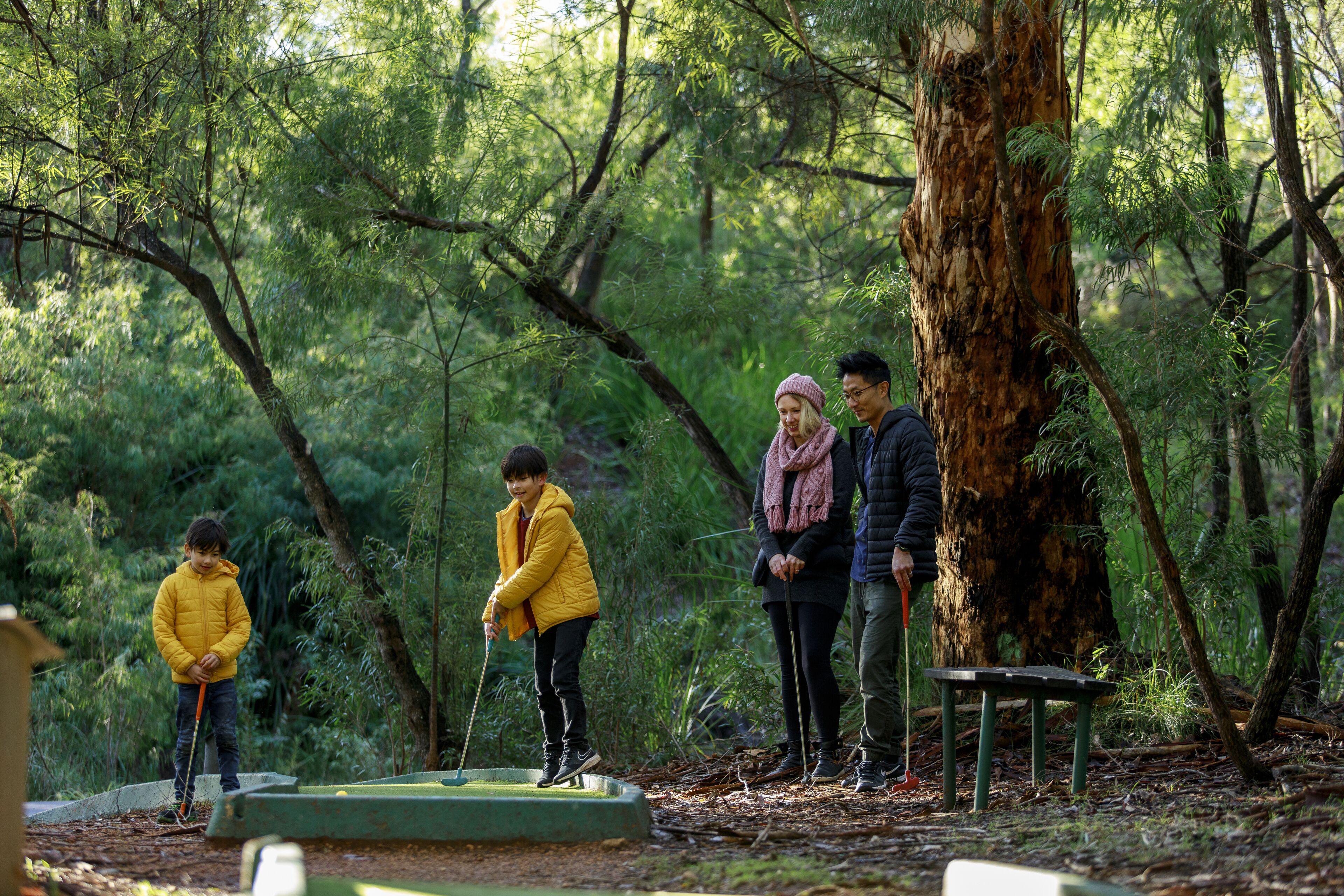 A group of people in a forested area with a small table and benches.