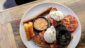 A plate with bacon, eggs, toast, beans, and a grilled tomato.