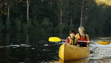 Two people in a canoe on a calm body of water surrounded by trees.