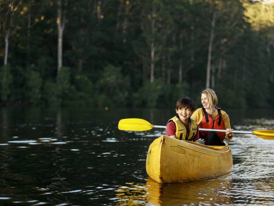 Two people in a canoe on a calm body of water surrounded by trees.