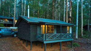 Une cabane en bois dotée d’un balcon, entourée de grands arbres.