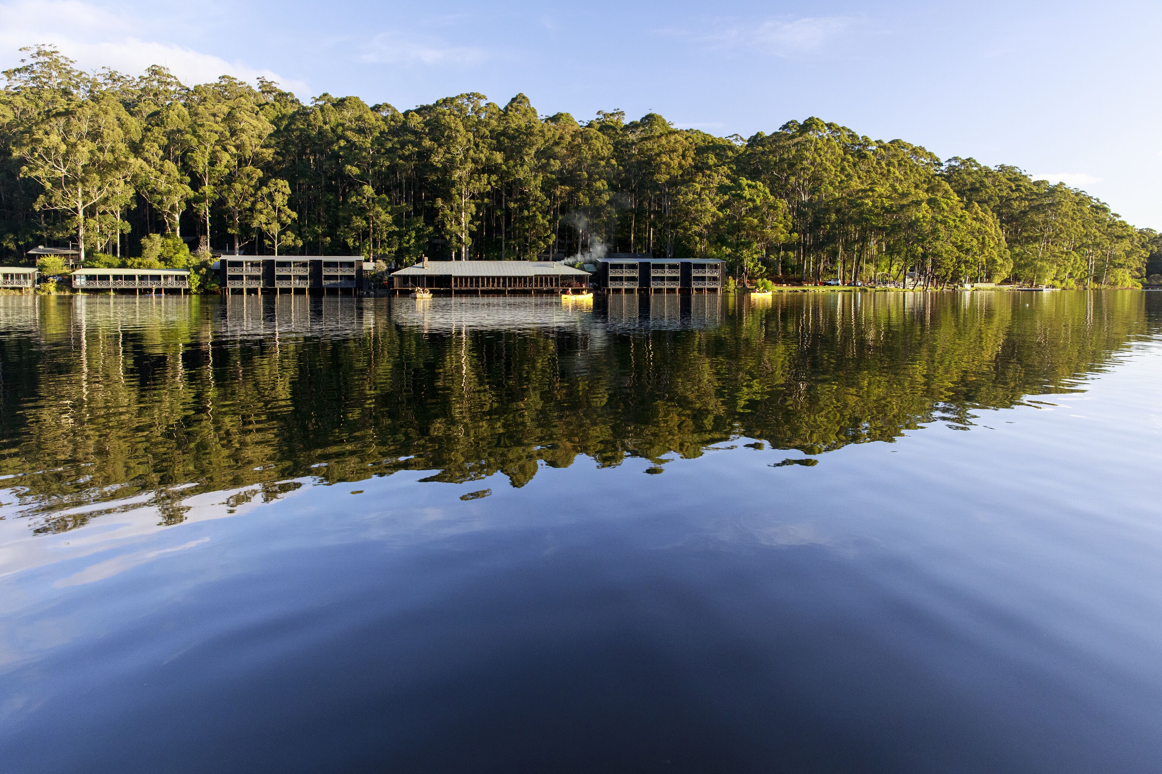 Une propriété au bord du lac, dotée de plusieurs structures flottantes et entourée d’une forêt dense.
