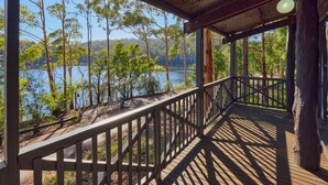 Une terrasse en bois avec une rambarde donnant sur un lac et des arbres.