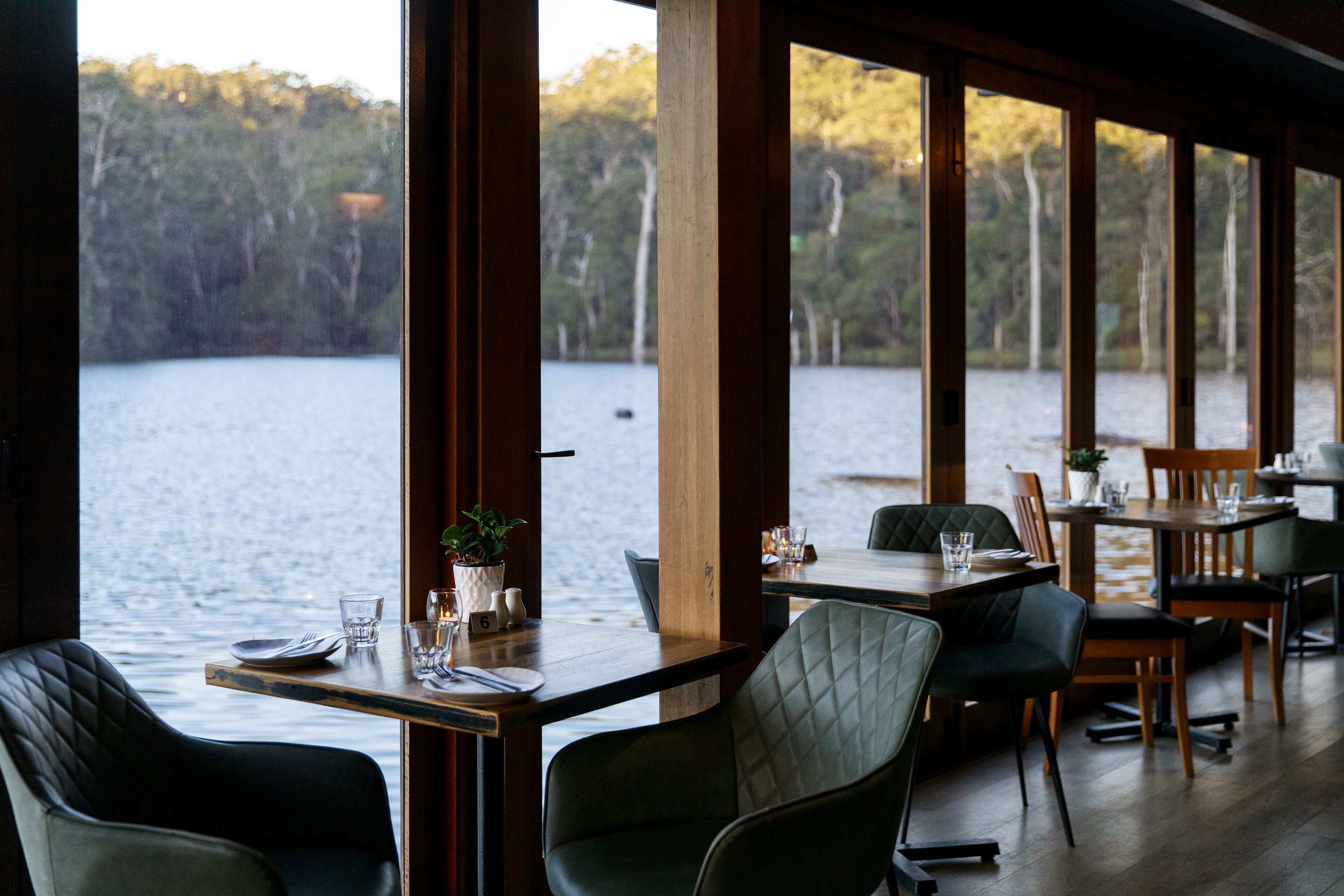 Un restaurante con mesas y sillas frente a un lago.