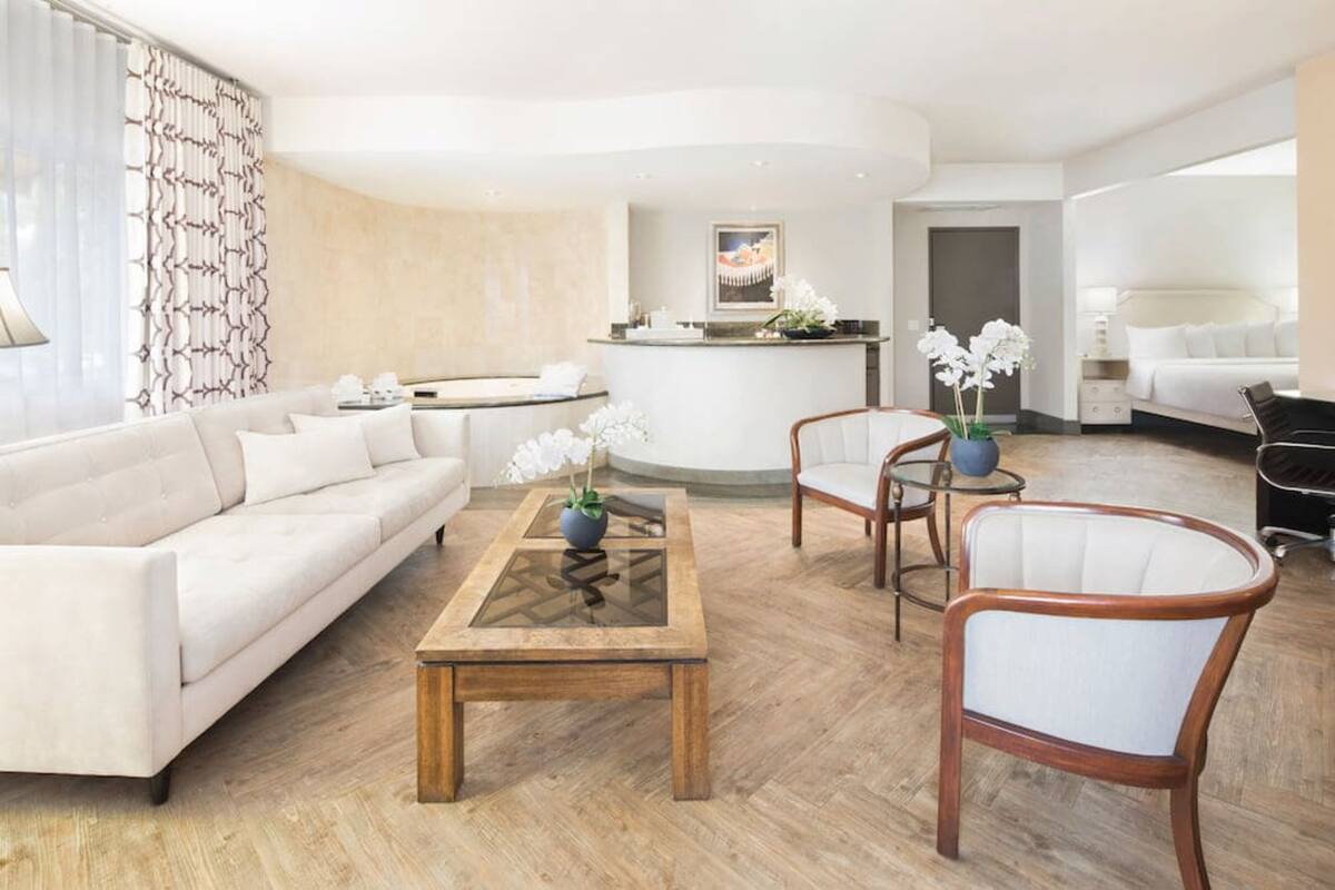A modern hotel lobby with a reception desk, a sofa, a coffee table, and two chairs.