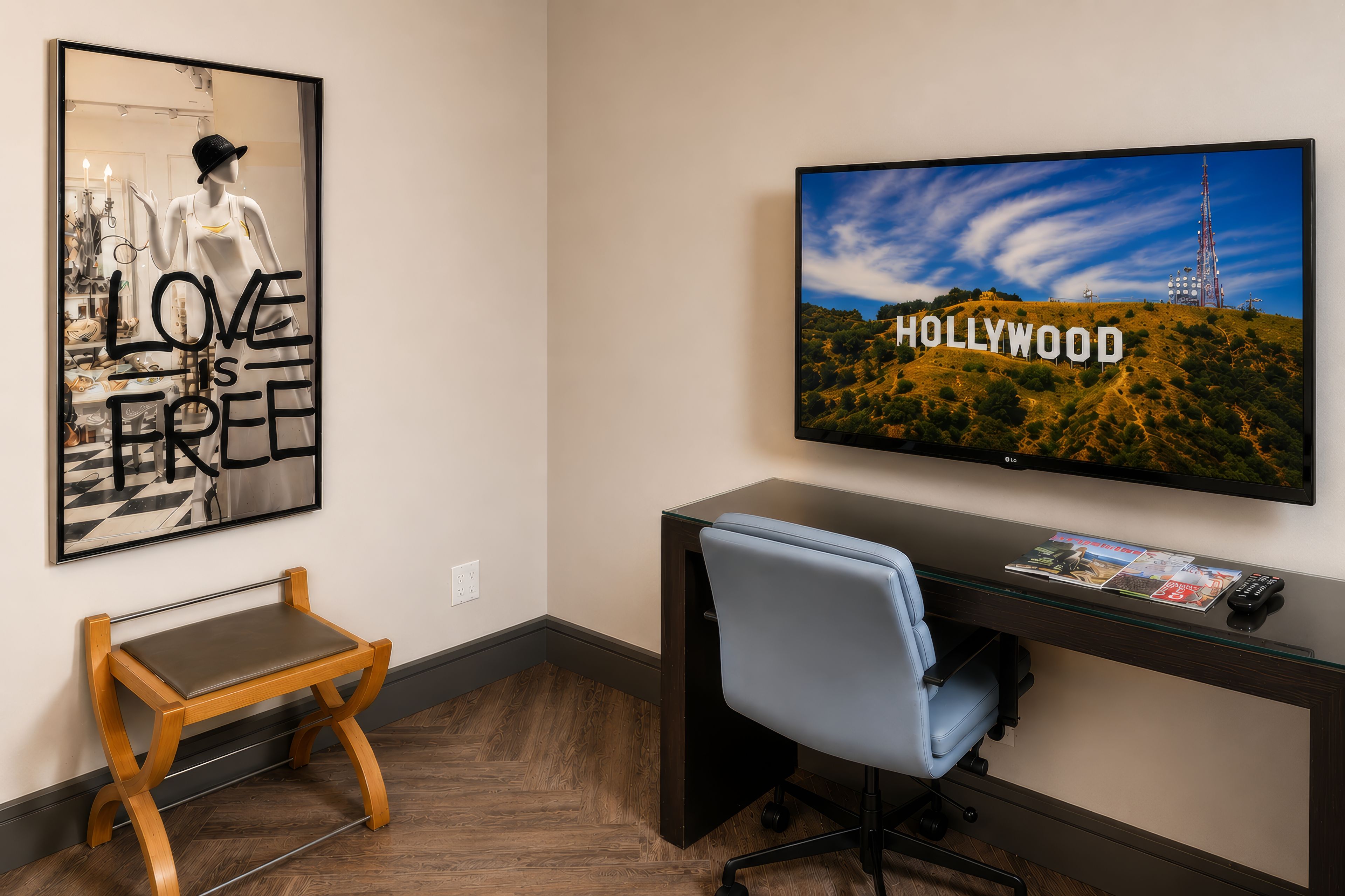 A room with a desk, a chair, a television displaying the Hollywood sign, and a framed picture on the wall.