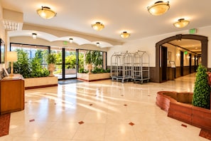 A spacious lobby with a reception desk, potted plants, and a clear view of the outdoors. - Hollywood Hotel (Los Angeles)