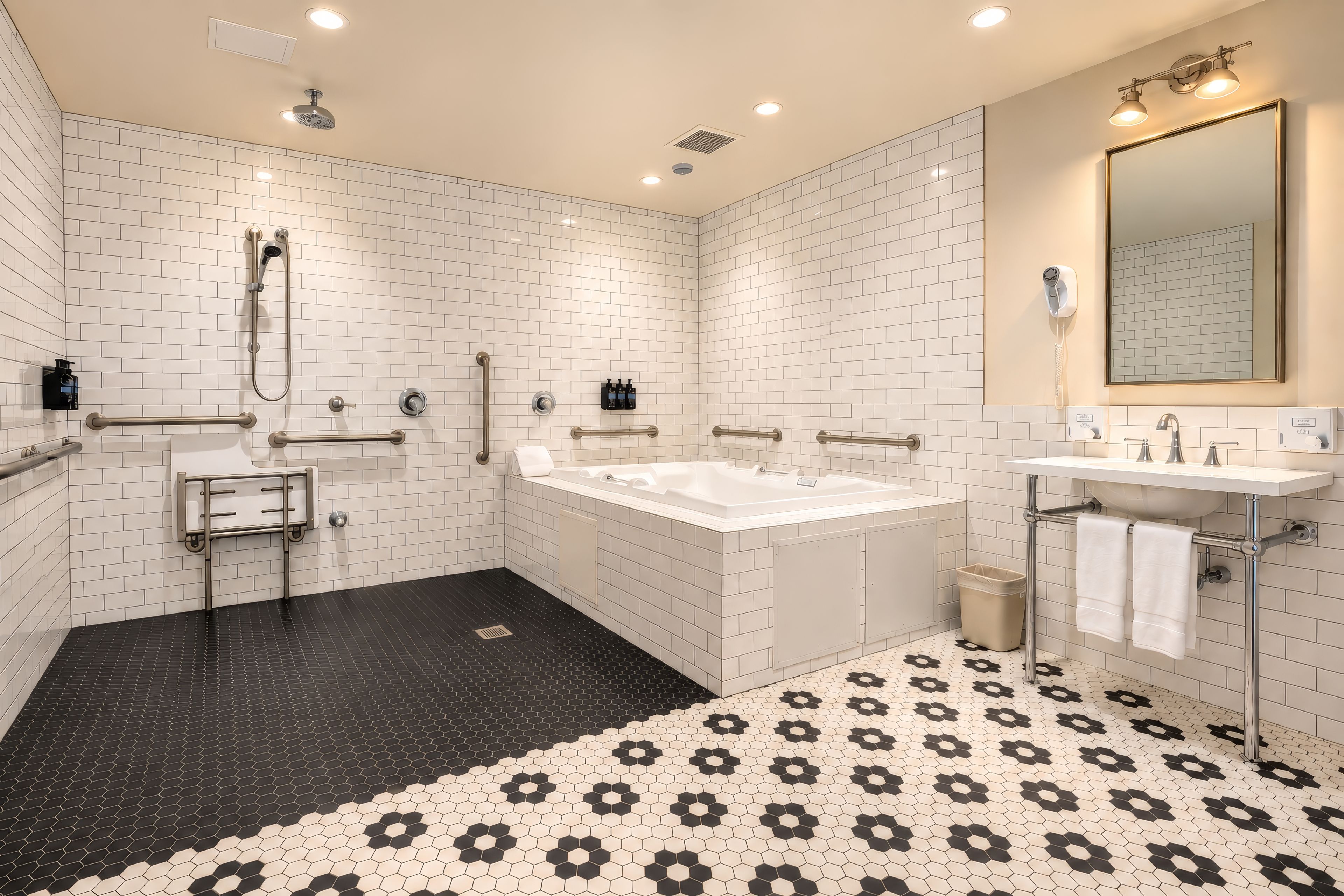 A modern bathroom with white subway tiles, a black and white patterned floor, a large bathtub, a separate shower area, and a vanity with a mirror.