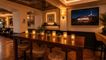 A bar area with a long wooden table, multiple candles, and stools.