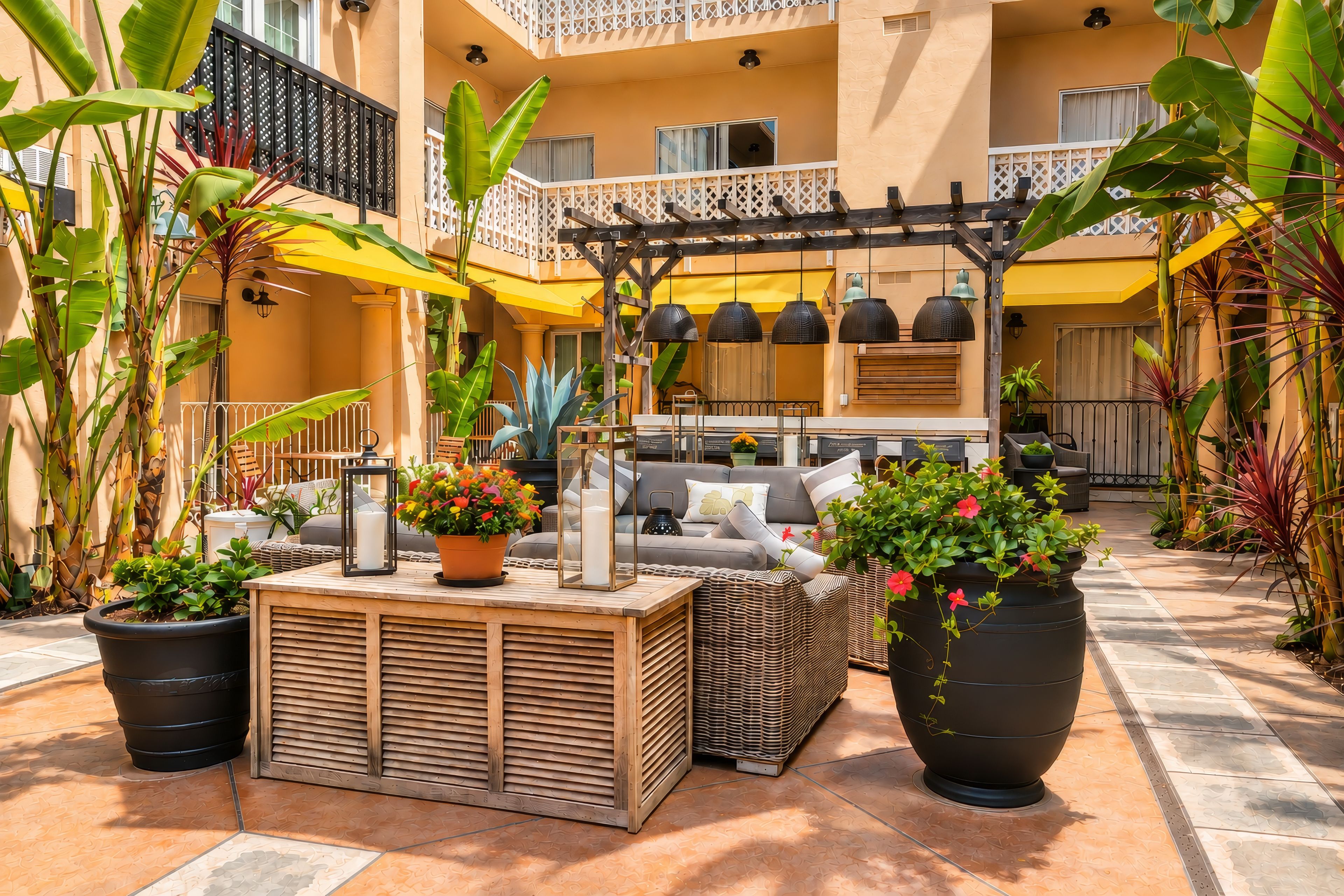 Un patio con zona de estar, plantas en macetas y una pérgola con luces colgantes.