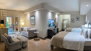 Quarto de hotel moderno com sofá, duas camas, televisão e escrivaninha.