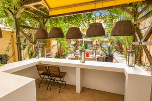An outdoor dining area with a white table, wicker lamps, and potted plants. - Hollywood Hotel (Los Angeles)