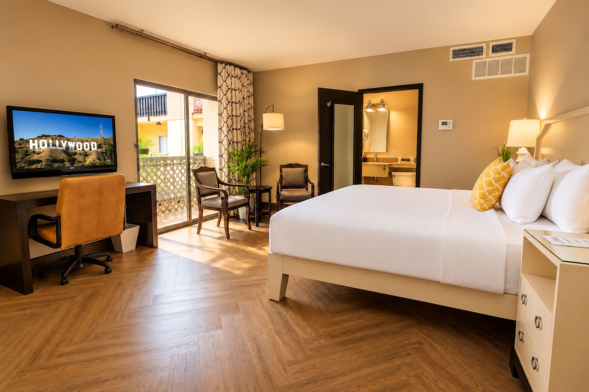 A hotel room with a bed, a desk, a chair, a television, and a bathroom.