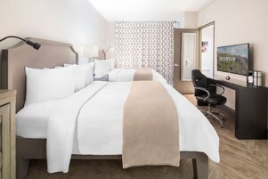 Een hotelkamer met een bed, bureau, stoel, televisie en een kamer met een patroon.