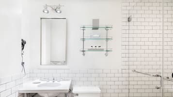 Un baño moderno con un lavamanos blanco, espejo y repisas de vidrio.