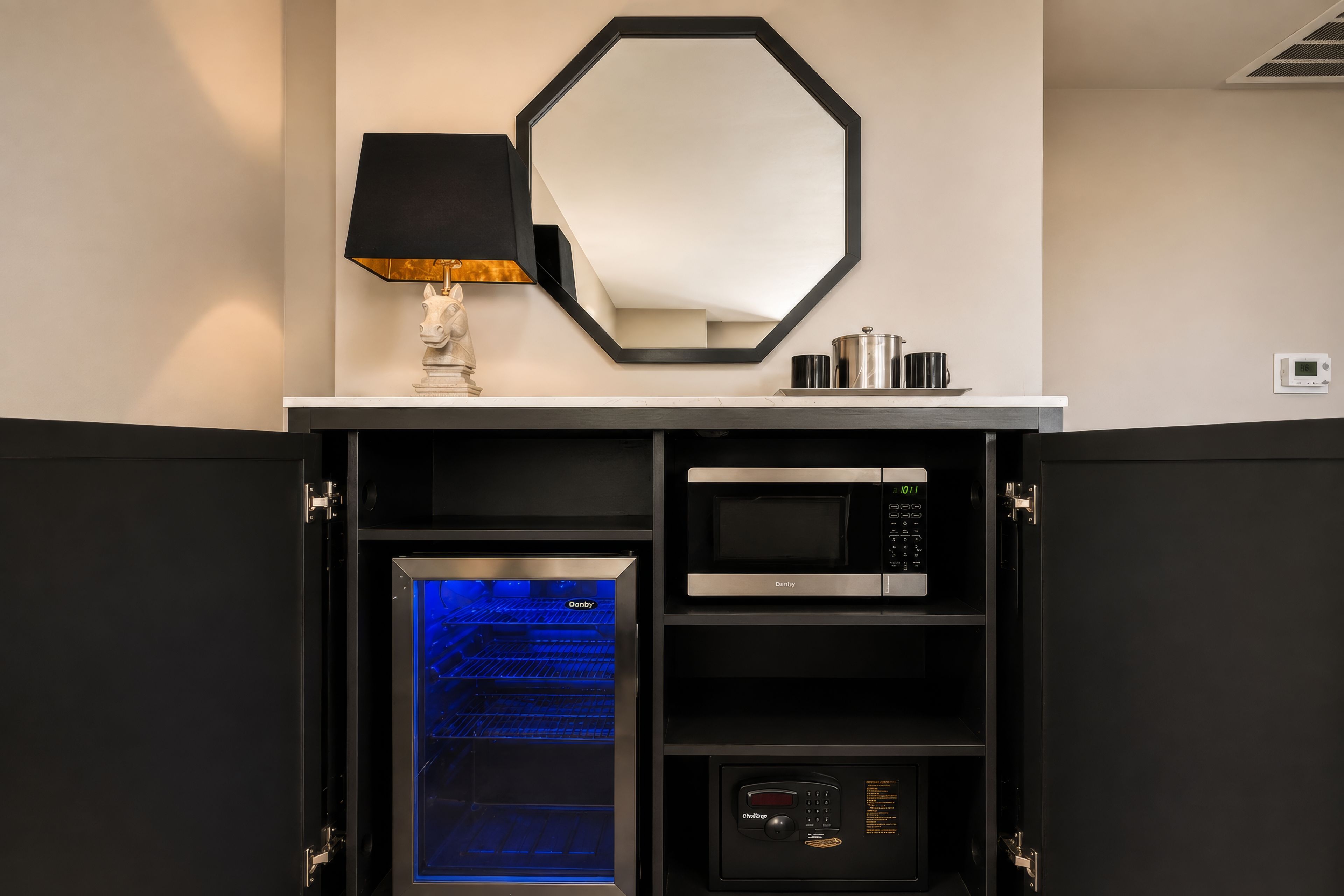 A kitchen with a built-in oven, microwave, and a digital clock on the wall.