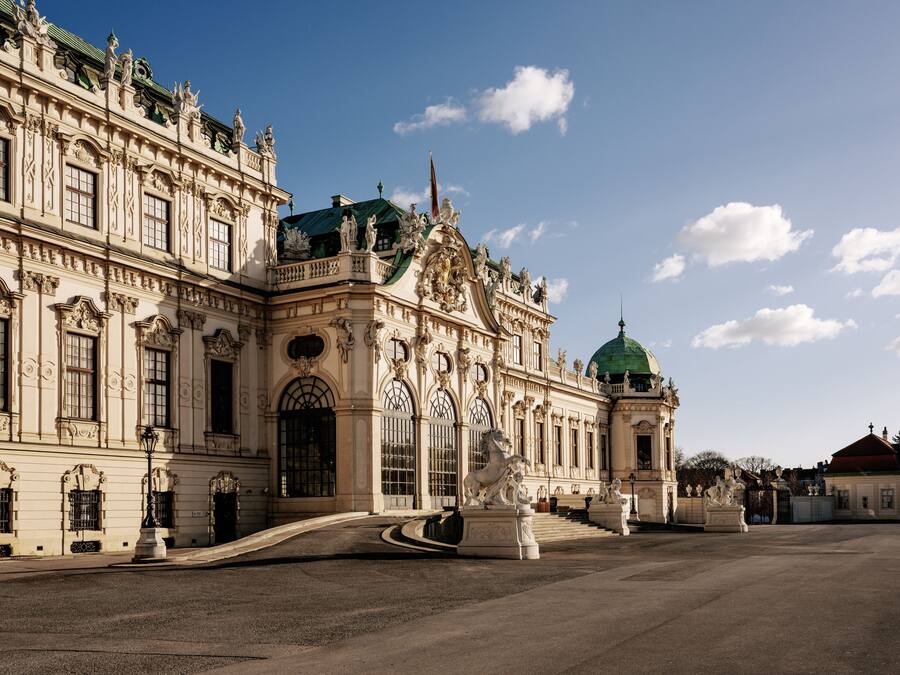 Un edificio imponente con arquitectura ornamentada, ventanas amplias y estatuas.