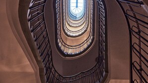 Eine mehrstöckige Wendeltreppe mit einem Oberlicht in der Mitte und runden Leuchten.