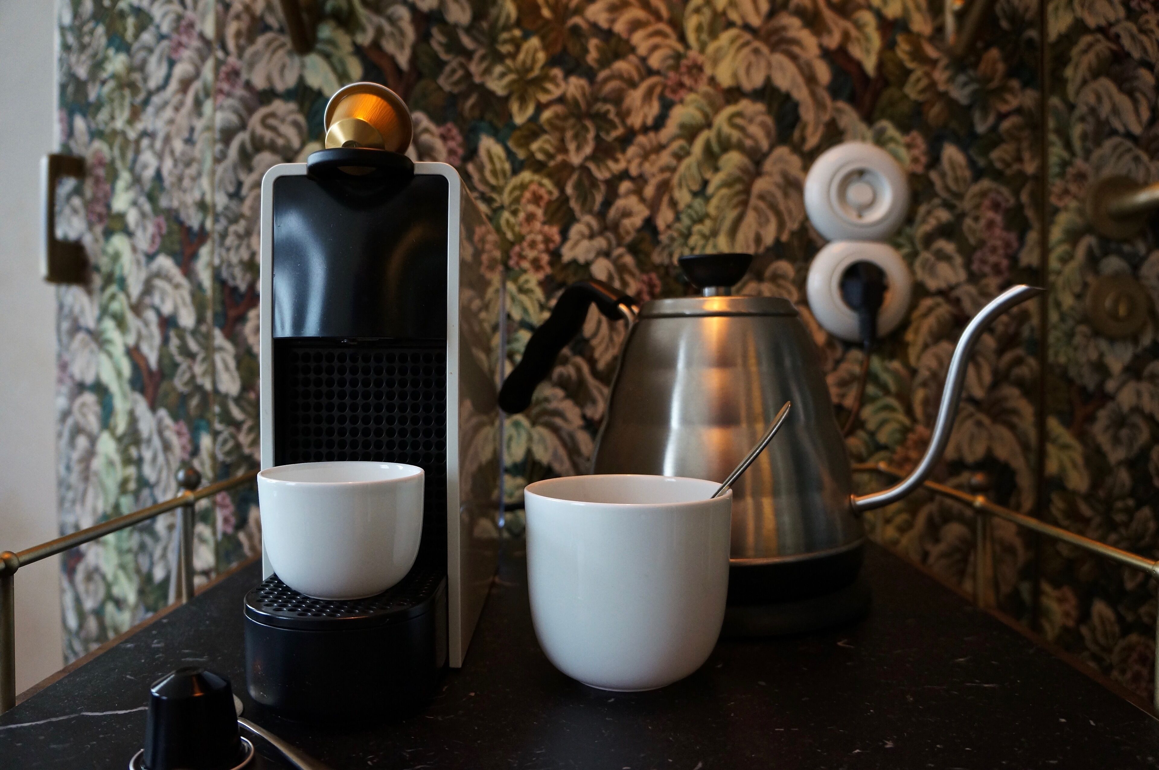 Une machine à café avec deux tasses et une bouilloire posées sur un comptoir.