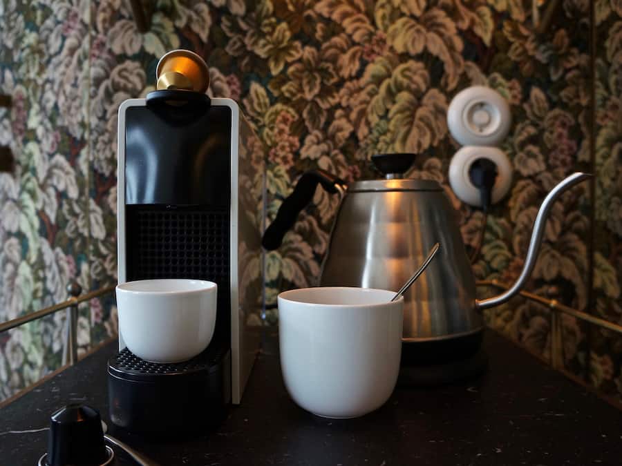 Una cafetera con dos tazas y una tetera sobre una encimera.