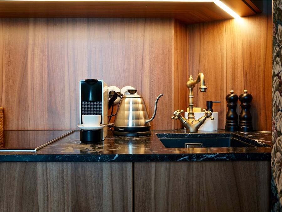 Uma cozinha com cafeteira, chaleira e pia.