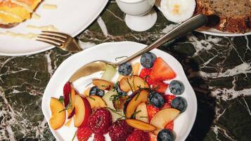 A dining table with various dishes, including a plate of salmon, a bowl of fruit, and a slice of bread.