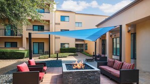 A courtyard with outdoor seating, a fire pit, and a covered area.