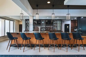A modern bar area with wooden bar counters, black bar stools, and pendant lighting. - Courtyard by Marriott Medical Center San Antonio (San Antonio)