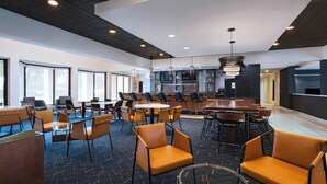 A modern hotel lobby with a mix of seating arrangements, including round tables and sofas, and a bar area with a high counter.
