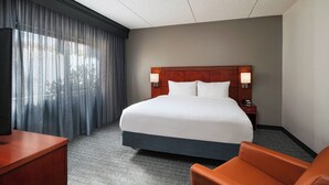 A hotel room with a large bed, a desk, and a chair.