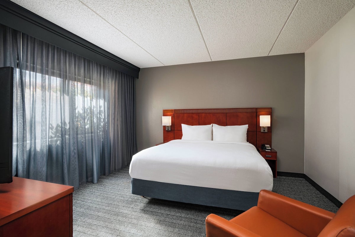 A hotel room with a large bed, a desk, and a chair.