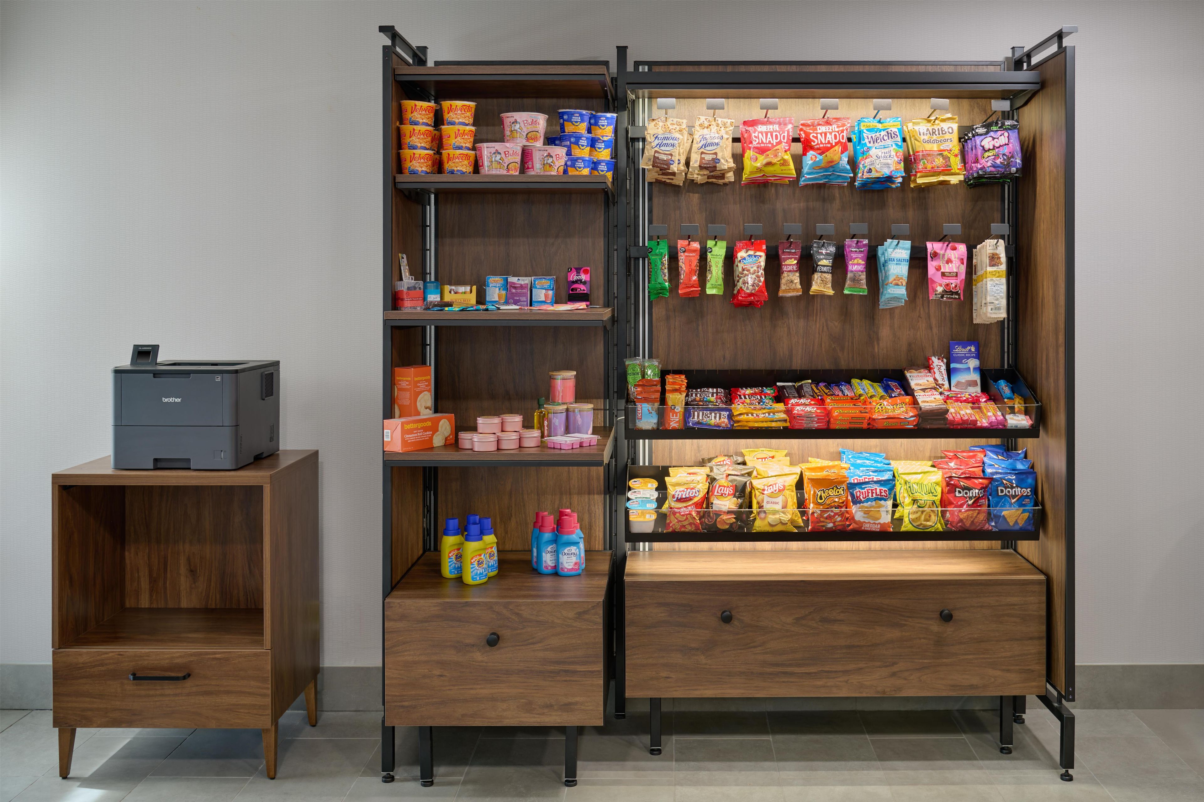 A storage unit with shelves containing various food items and a printer on a wooden cabinet.