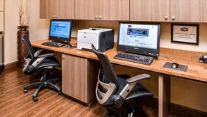 Ein Hotel-Empfangsbereich mit zwei Computertischen, einem Drucker und einem gerahmten Schild.