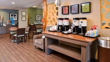 Un vestíbulo de hotel con una estación de café, zona de estar y un mostrador de recepción.